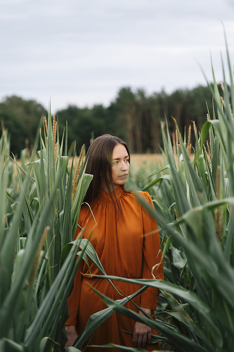 Thoughtful woman standing amidst corn crops in field