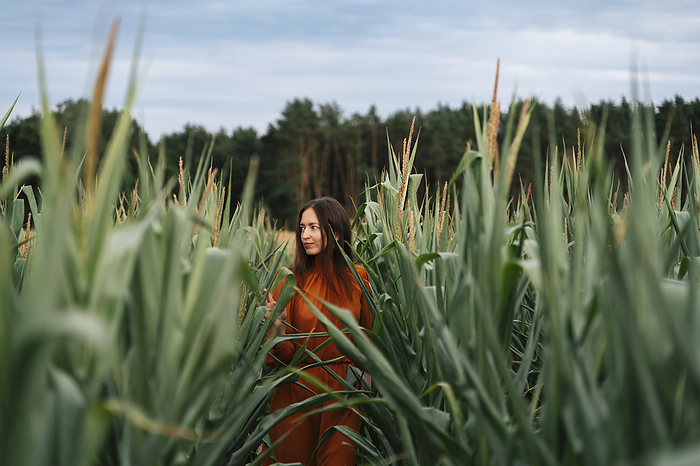 Woman walking amidst corn crops in field