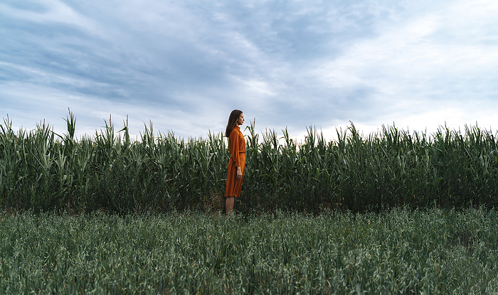 Woman standing by corn crops growing in field