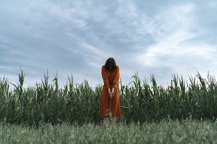 Woman standing in front of corn crops at field