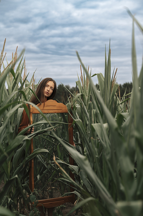 Woman carrying mirror amidst corn crops in field