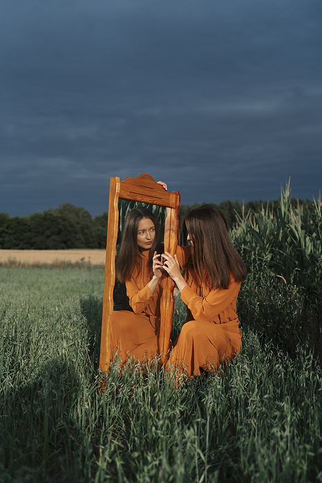 Woman with reflection in mirror at corn field