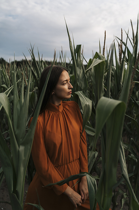 Thoughtful woman amidst corn crops in field