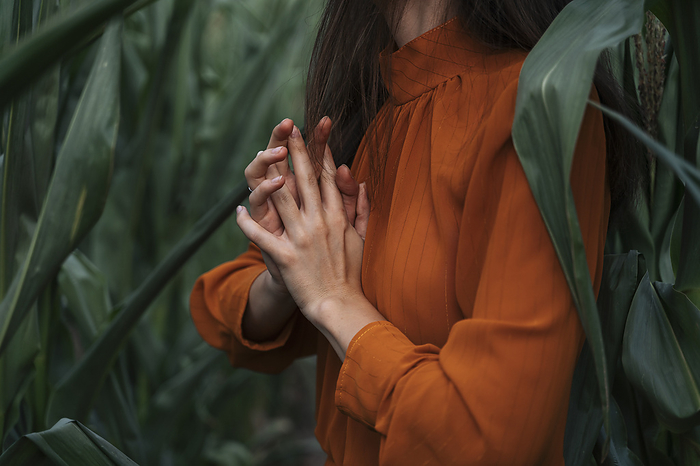 Woman with hands clasped amidst corn crops in field
