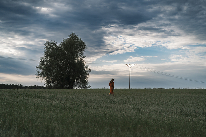 Woman walking in corn field at sunset