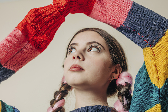 Young woman wearing multi colored sweater near wall