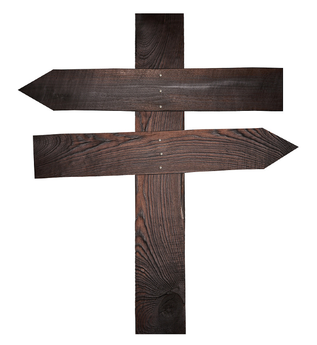 Wooden boards nailed together in the form of arrows on a pole, a direction indicator. Isolated background Wooden boards nailed together in the form of arrows on a pole, a direction indicator. Isolated background