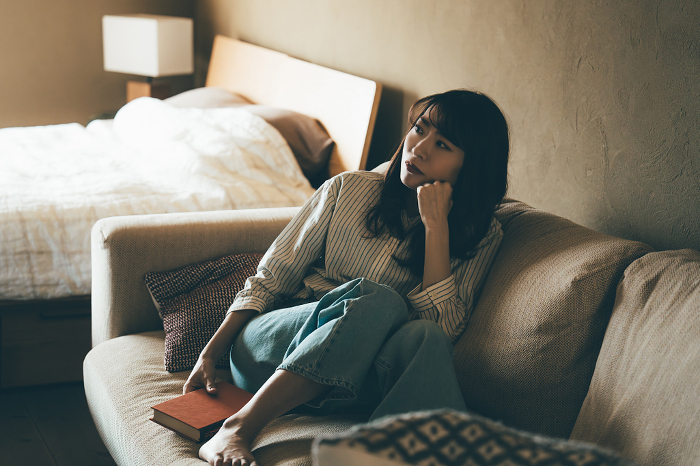 Japanese woman thinking on the sofa (People)