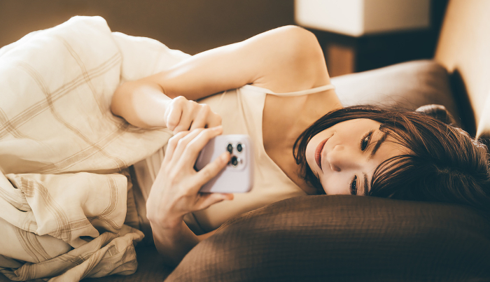 Japanese woman using smartphone in bed (People)