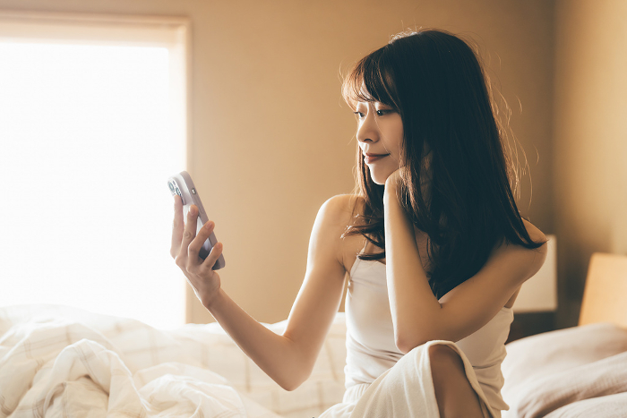 Japanese woman using smartphone in bed (People)
