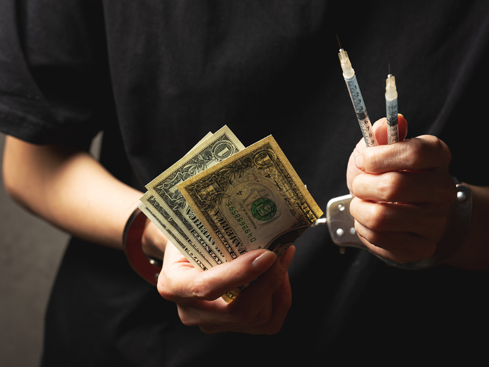 Handcuffed woman's hand and syringe Drug image