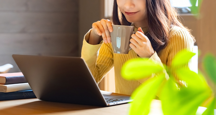 Smiling Japanese woman using a laptop computer while sipping a drink (People)