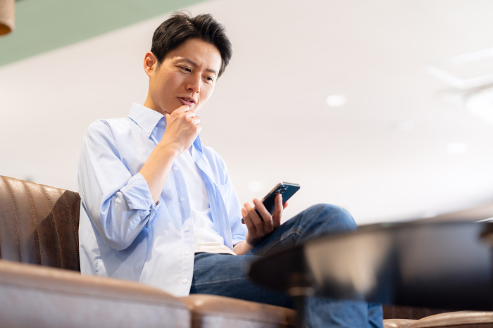 Middle Japanese man looking at his phone in a cafe.