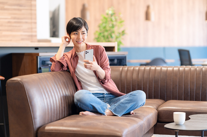 Young Japanese woman looking at her phone in a cafe (People)