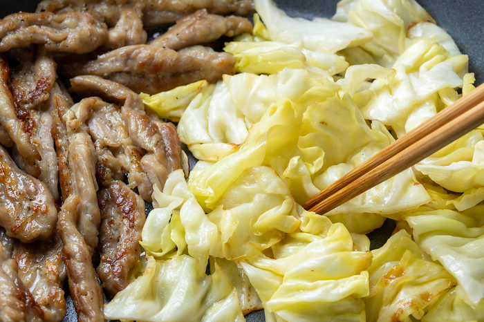 Cooking scene of pan frying chicken (cecelery) and cabbage.