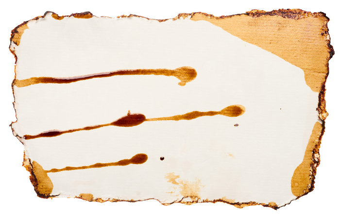 White torn piece of paper drenched in coffee on an isolated background White torn piece of paper drenched in coffee on an isolated background