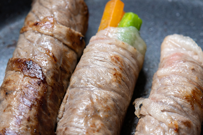 Asparagus and carrots wrapped with beef, cooking scene.