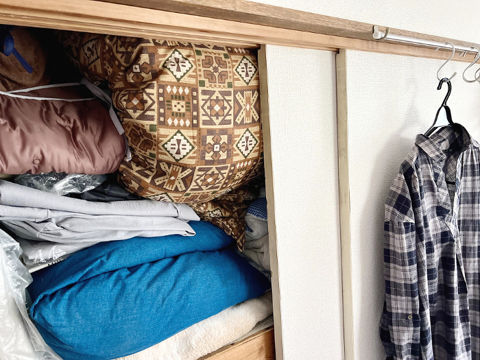 A closet full of futons and clothes on hangers
