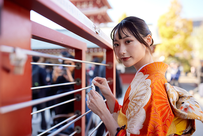 Japanese woman in furisode kimono tying a fortune