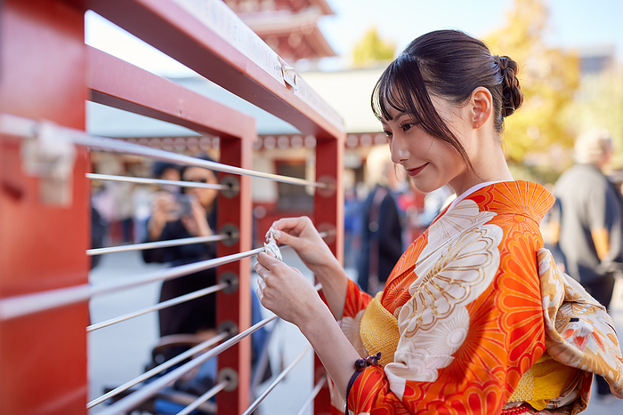 Japanese woman in furisode kimono tying a fortune