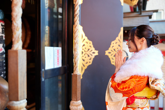 Japanese woman in furisode (long-sleeved kimono) paying a visit to a shrine