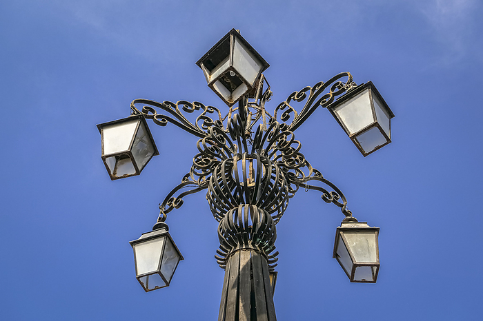 Low angel view of an artful metal pole with five lanterns against blue sky, Old Town, Cartagena, Col Low angel view of an artful metal pole with five lanterns against blue sky, Old Town, Cartagena, Col, by Zoonar Uwe Bergwitz