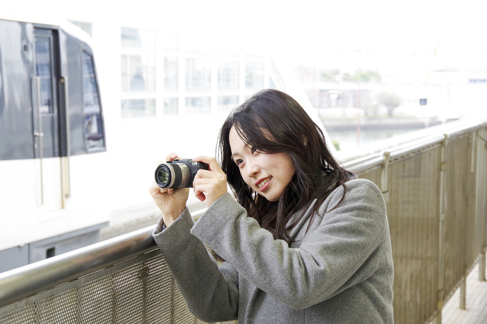 Woman photographing a train from a station platform