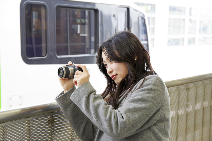 Woman photographing a train from a station platform