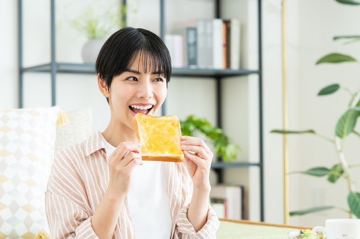 Young Japanese woman eating breakfast in the living room (People)