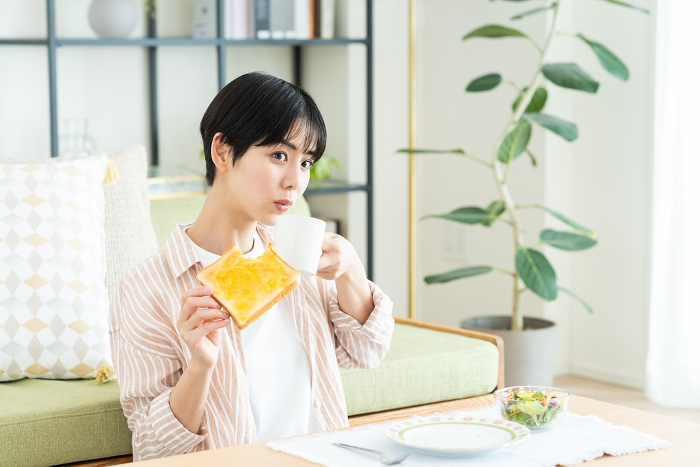 Young Japanese woman eating breakfast in the living room (People)