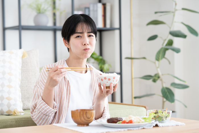 Young Japanese woman eating lunch in the living room (People)