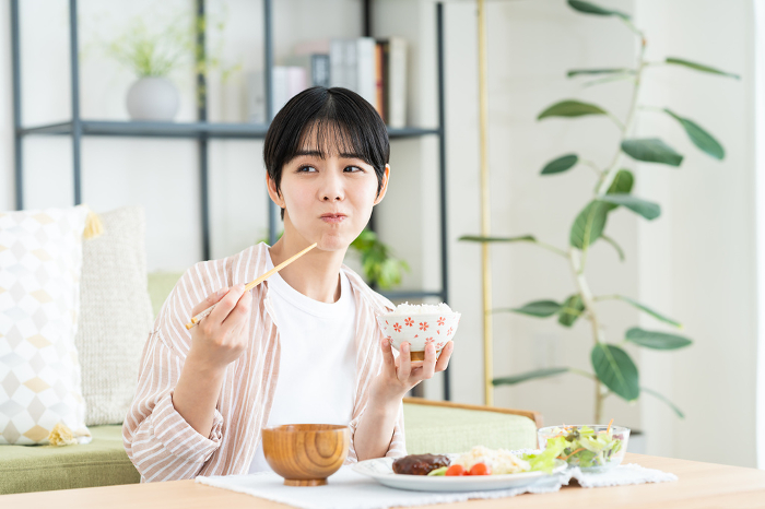 Young Japanese woman eating lunch in the living room (People)