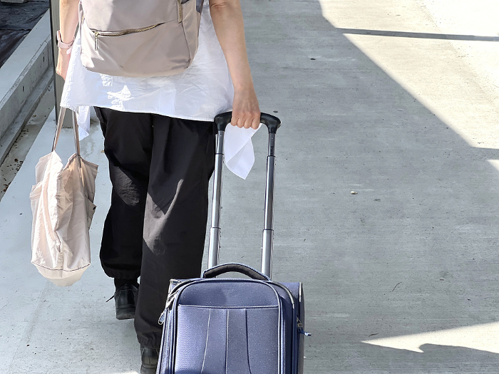 Rear view of a woman walking while pulling a carry-on bag