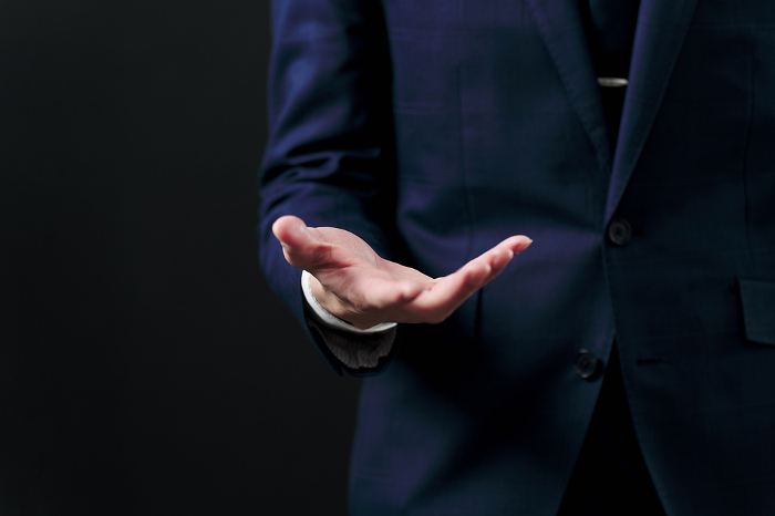 Japanese businessman holding out his hand against black background (People)