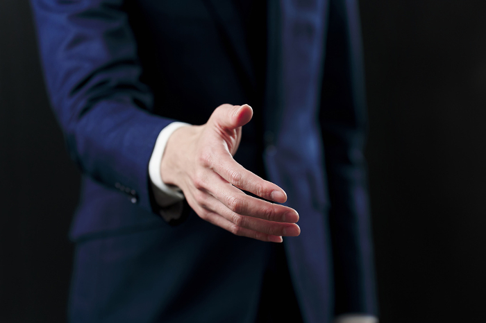 Japanese businessman shaking hands against black background (People)
