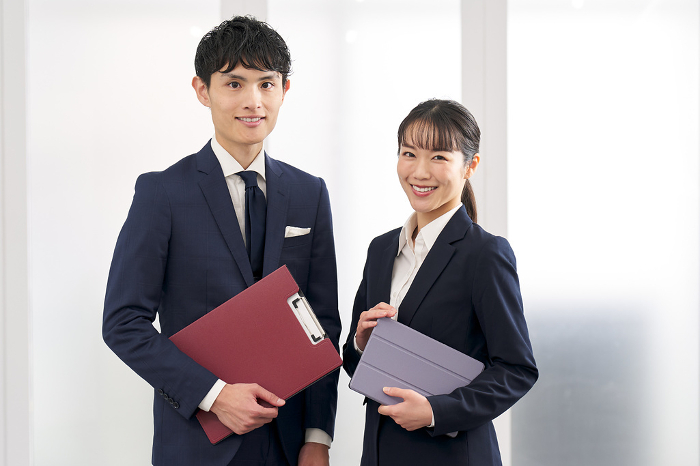 Japanese businesspersons, male and female, standing in office (People)