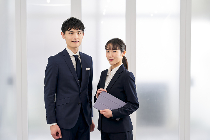 Japanese businesspersons, male and female, standing in office (People)