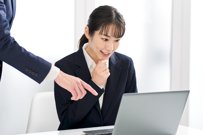 Japanese businesswoman being told she made a mistake at work （Female / People)