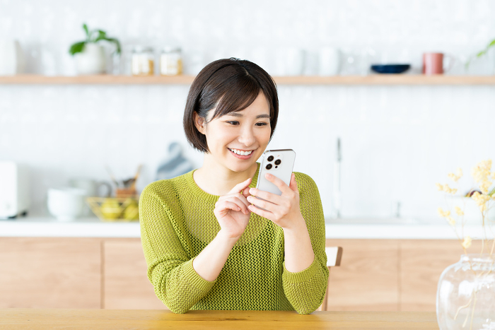 Young Japanese woman using her phone in the kitchen/dining room (People)