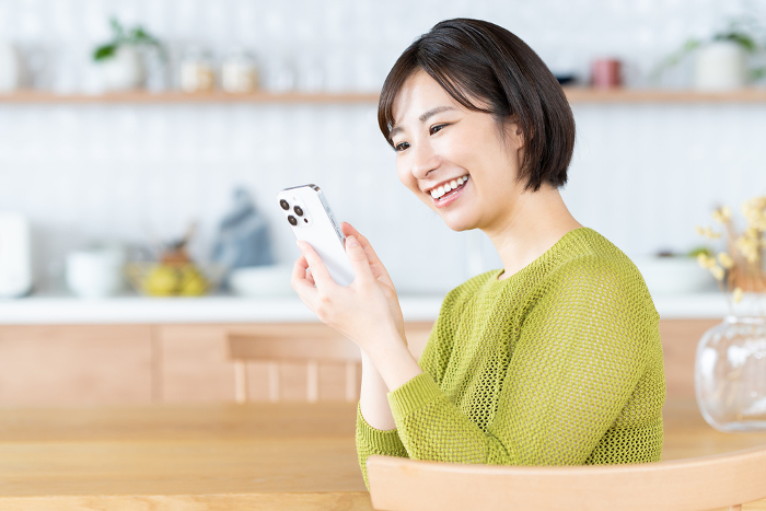 Young Japanese woman using her phone in the kitchen/dining room (People)