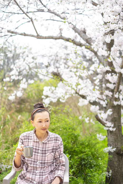 Woman having breakfast in a garden with cherry blossoms