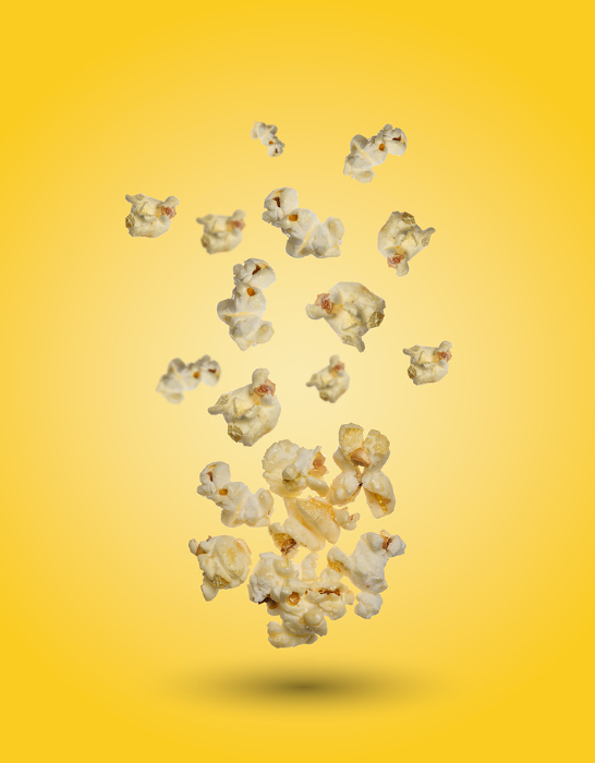Sweet popcorn on yellow background, grains levitate Sweet popcorn on yellow background, grains levitate