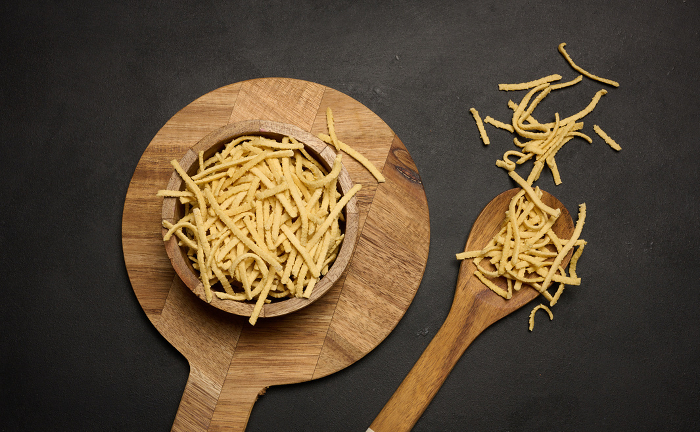 Raw wheat noodles in wooden bowl, top view Raw wheat noodles in wooden bowl, top view