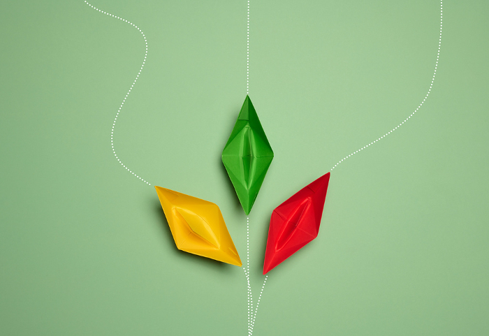 Paper boats on a green background with paths of movement, representing the concept of individuality. Top view Paper boats on a green background with paths of movement, representing the concept of individuality. Top view
