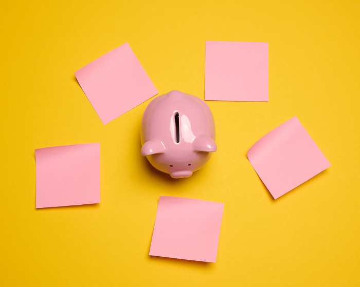 Pink ceramic piggy bank and paper stickers on a yellow background, top view Pink ceramic piggy bank and paper stickers on a yellow background, top view