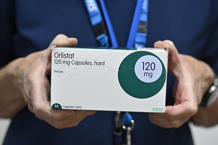 Orlistat anti obesity drug Box containing capsules of the anti obesity drug orlistat. It inhibits the production of pancreatic lipase, an enzyme that breaks down fat in the intestine. Without the enzyme, fat from the diet is excreted undigested. Side effects include loose, oily faeces., by DR P. MARAZZI SCIENCE PHOTO LIBRARY