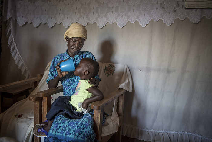 Girl drinking a mug of milk, Kenya Grandmother holding a mug of milk while her granddaughter drinks it. Photographed in Kopiyo, Homa Bay County, Kenya., by KAREN KASMAUSKI SCIENCE PHOTO LIBRARY