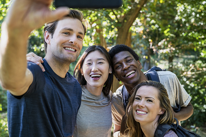 Young adult man taking a selfie with friends during hiking excursion