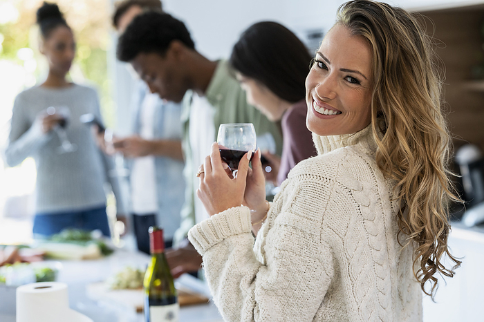 Cheerful adult woman looking back at the camera while holding wineglass