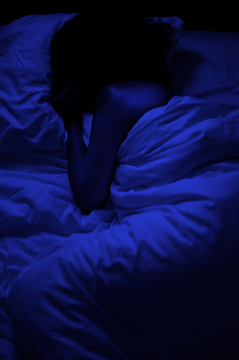 Person sleeping in bed in darkness